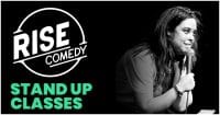 A person holding a microphone is on stage, smiling, with the words Rise Comedy Stand Up Classes beside them. The image is in black and white with the text in white and green on a black background.
