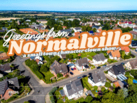 A postcard-style image shows an aerial view of a suburban town with houses, trees, and fields. Large text reads Greetings from Normalville, a small town character clown show. Spaces for TO: and FROM: are at the bottom.